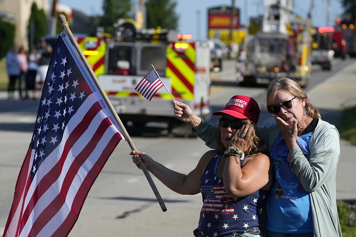 Merri Cambo, left, of Saxonburg, Pa., and her friend, Jane Wesolosky, of Buffalo, Pa., react as the funeral procession for Corey Comperatore passes by, Friday, July 19, 2024, in Sarver, Pa. Comperatore, a former fire chief, was shot and killed while attending a weekend rally for former President Donald Trump. (AP Photo/Matt Slocum)