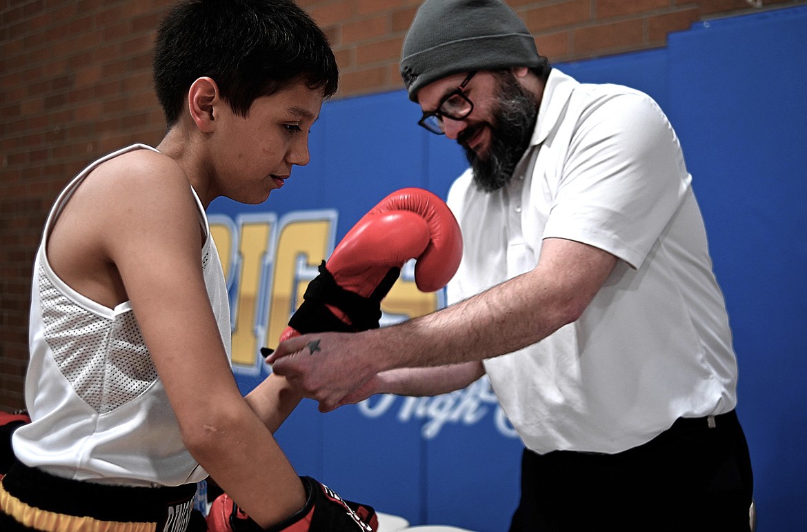 Bryan Dupuis Sr. helps his son, Ronald, with a boxing glove. (Screenshot from UM video by Ian Frank)