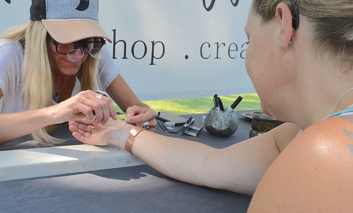 Colorado silversmith Jenny Kenyon adjusts a bracelet for Jamie Gralapp during Saturday's Flathead Lake Festival of Art, sponsored by the Sandpiper Gallery in Polson. (Kristi Niemeyer/Leader)