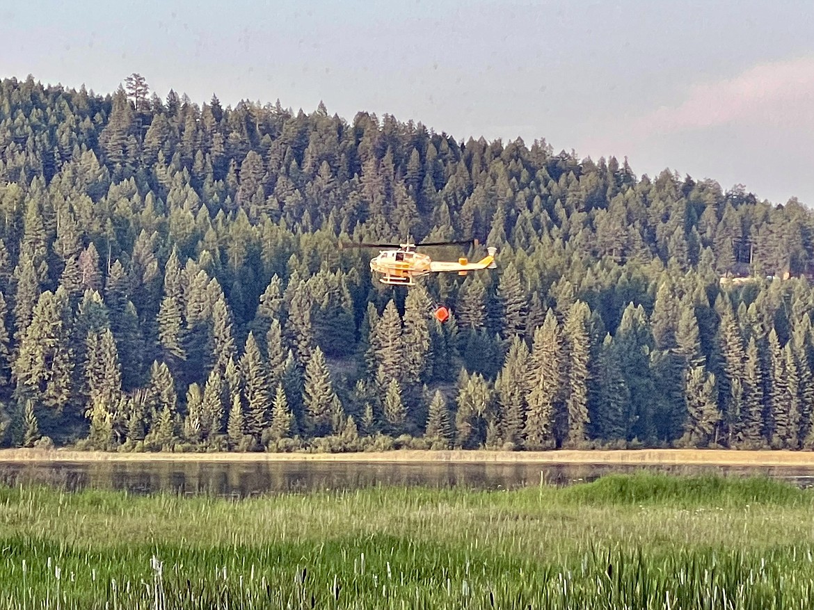 A helicopter with a water bucket scoops water from Skyles Lake and transports it to a small fire on Lion Mountain on Saturday Evening. (Matt Baldwin/Whitefish Pilot)