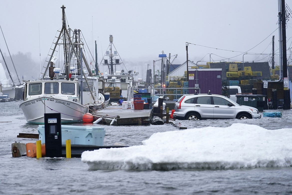 FILE - A car sits in a flooded parking lot at Widgery Wharf in this Jan. 10, 2024, in Portland, Maine. Dozens of waterfront communities around Maine will receive more than $21 million to help rebuild from a series of devastating storms that hit the state in the winter, Gov. Janet Mills announced Monday, July 22. (AP Photo/Robert F. Bukaty, File