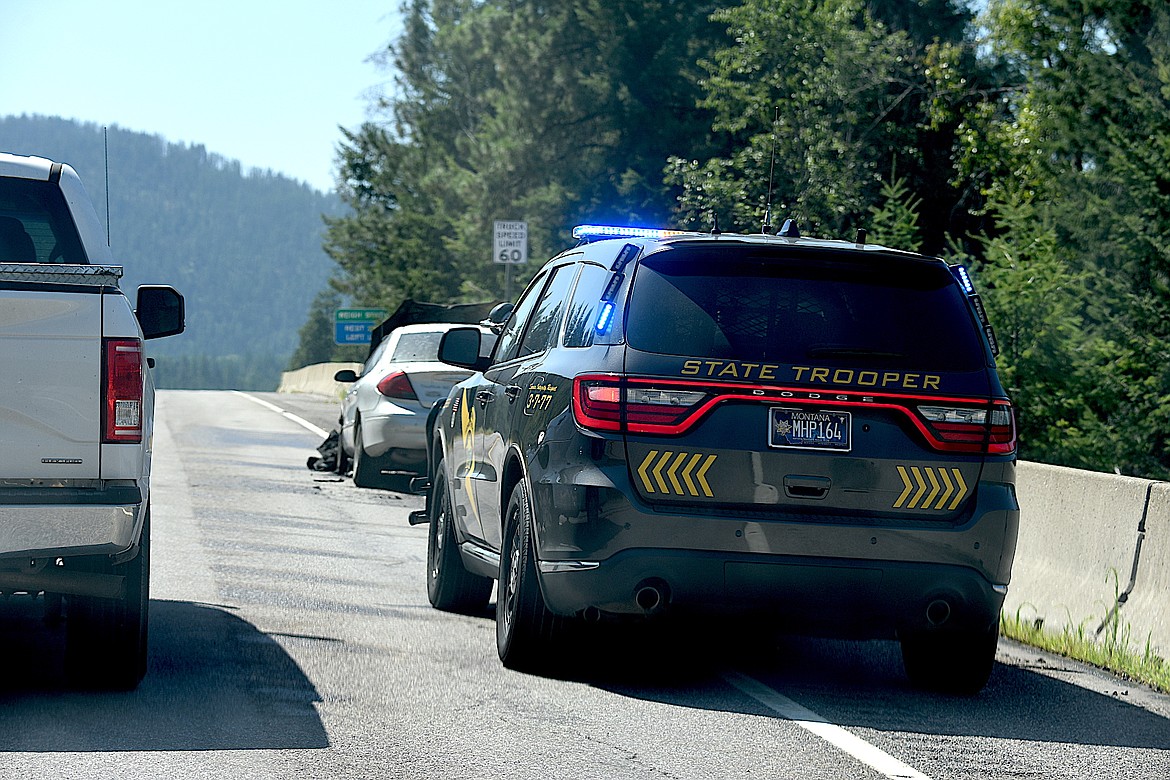 Montana Highway Patrol trooper Bryce Ford's vehicle shields a car from traffic on U.S. 2 near the Kootenai rest area at the intersection of Bull Lake Road. The car was severely damaged in a fire Tuesday afternoon. Troy Volunteer Fire Department members extinguished the blaze and prevented its spread to nearby conifer trees on a steep hillside above the Kootenai River. Traffic was backed up for several miles and about one hour. (Scott Shindledecker/The Western News)