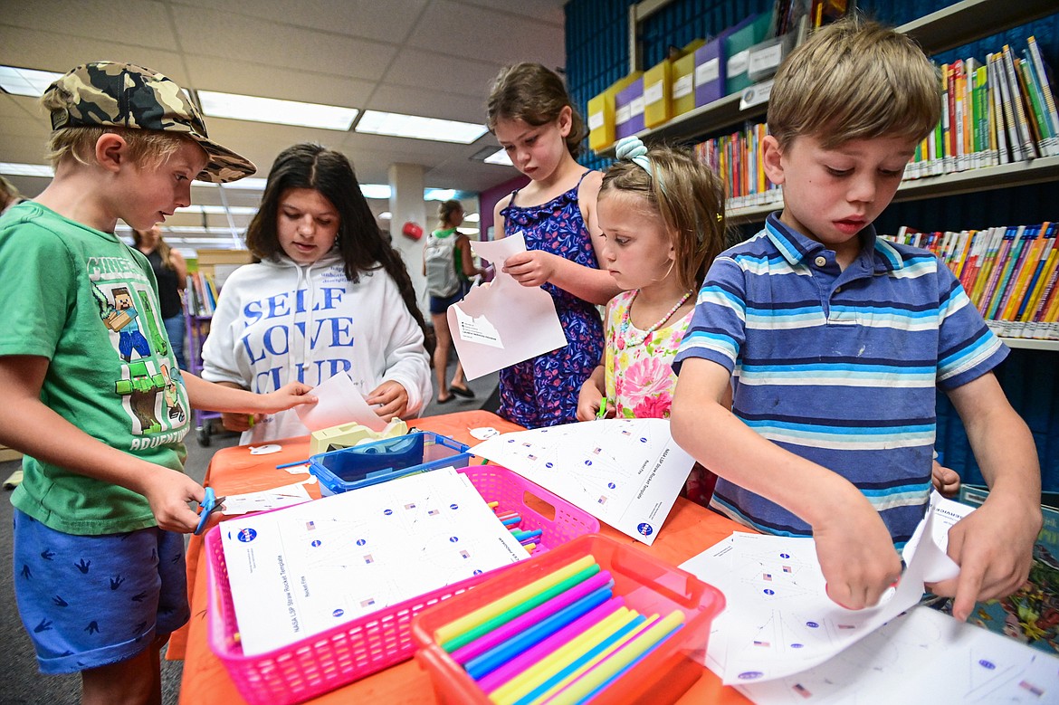 Kids cut out a template for a NASA straw rocket after a presentation by Jarrod Bales from NASA’s Kennedy Space Center at ImagineIF Library in Kalispell on Friday, July 26. (Casey Kreider/Daily Inter Lake)