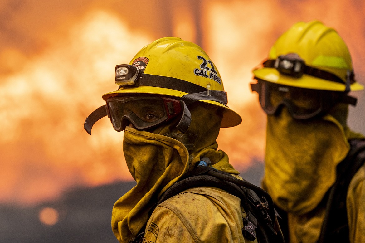 Cal Fire firefighter Christian Moorhouse, center, monitors the flames while defends a mobile home during the Park Fire in the community of Cohasset near Chico, Calif., Thursday, July 25, 2024. (Stephen Lam/San Francisco Chronicle via AP)