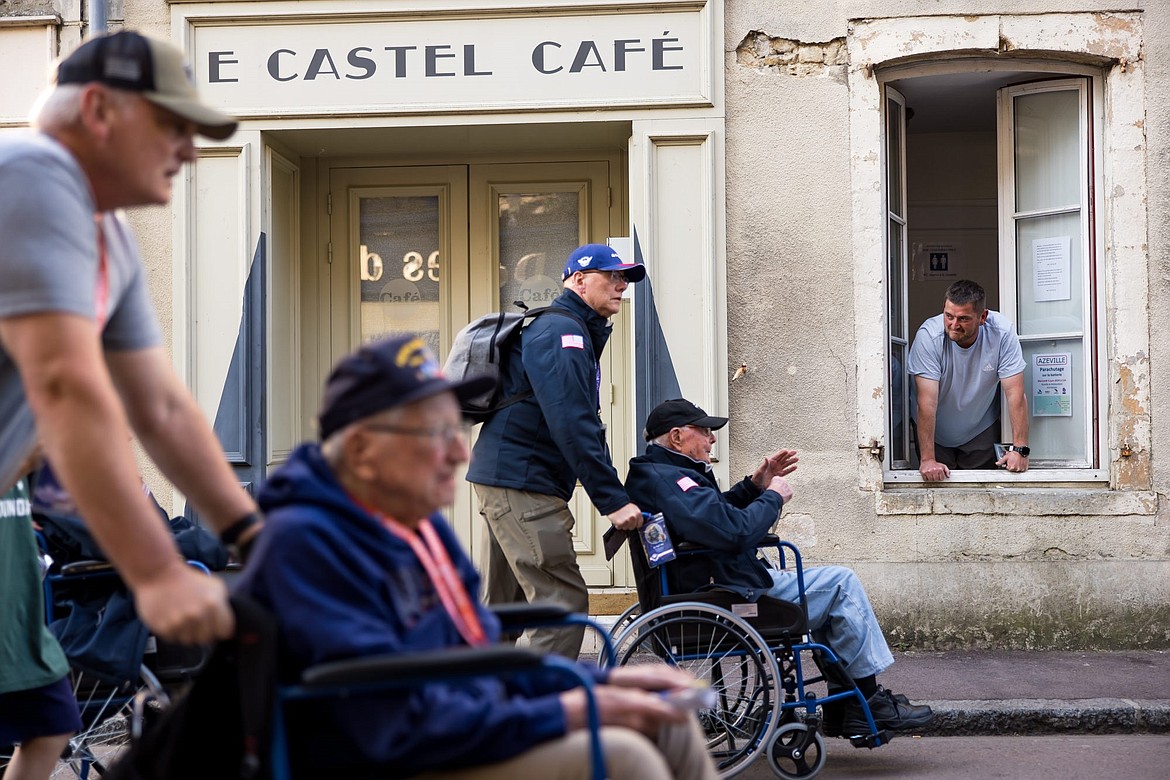 A local watches as veterans and their caregivers walk through the streets of Sainte-Mère-Église in the Normandy region of France on Sunday, June 9, 2024.