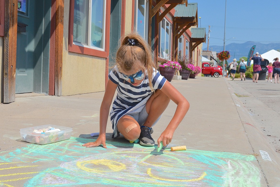 Elsie Rogers puts finishing rouches on her chalk art masterpiece during last weekend's Flathead Cherry Festival in Polson. (Kristi Niemeyer/Leader)