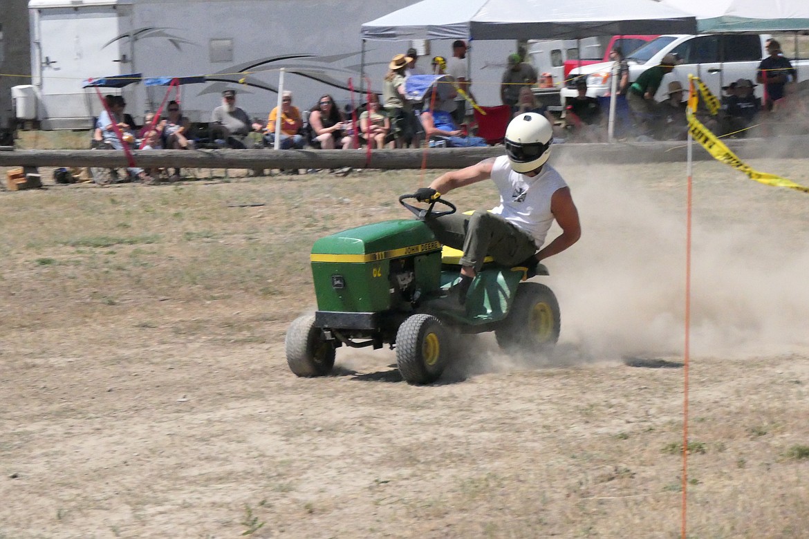 A lawn mower racer riding his John Deere machine holds on during a fast turn around one of the track's tight corners.