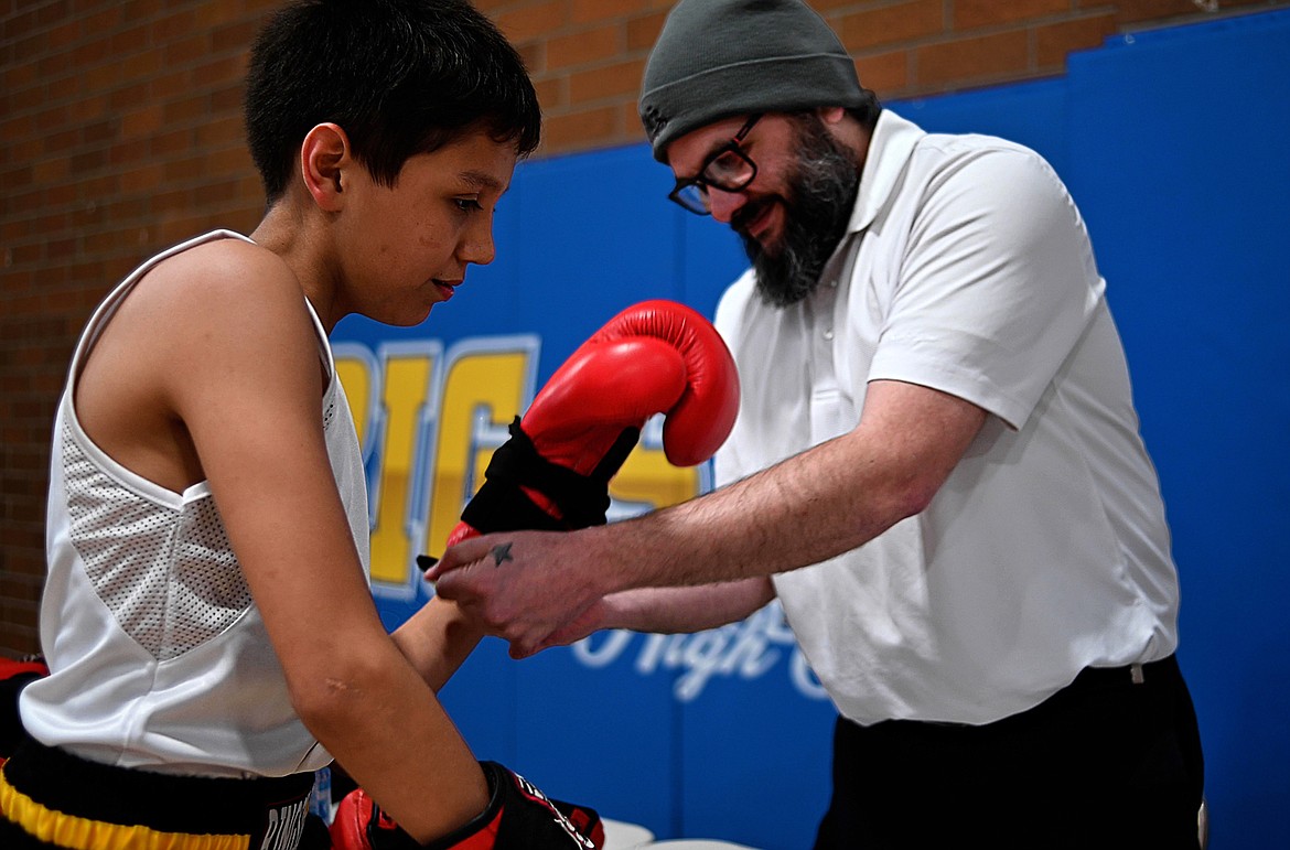 Bryan Dupuis Sr. helps his son, Ronald, with a boxing glove. (Screenshots from UM video by Ian Frank)