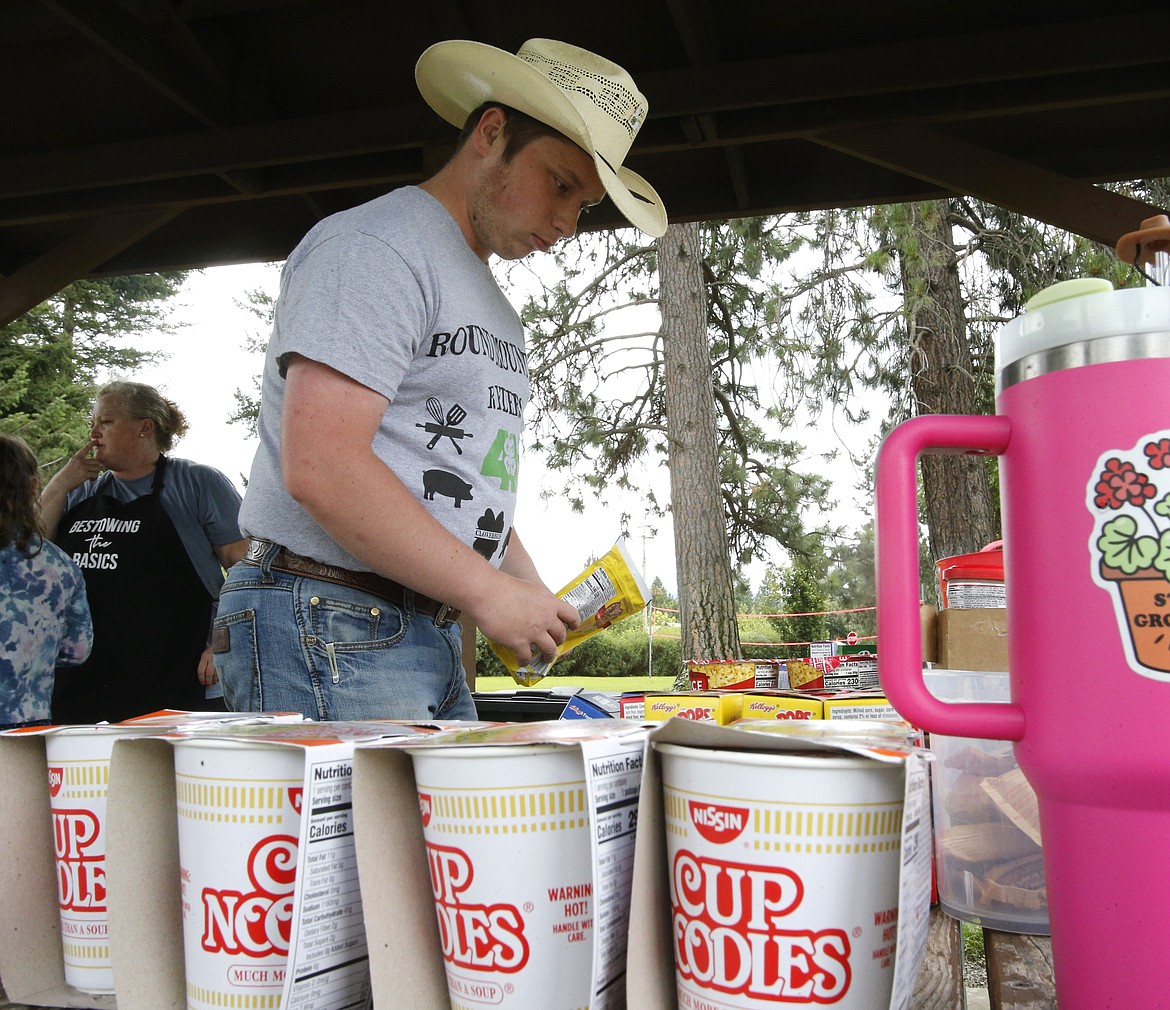 Bestowing the Basics volunteer Matthew Murray, 20, of Rathdrum, organizes boxes of Kellogg's Corn Pops and Nissin Cup Noodles before free lunches are served Tuesday in Athol City Park.