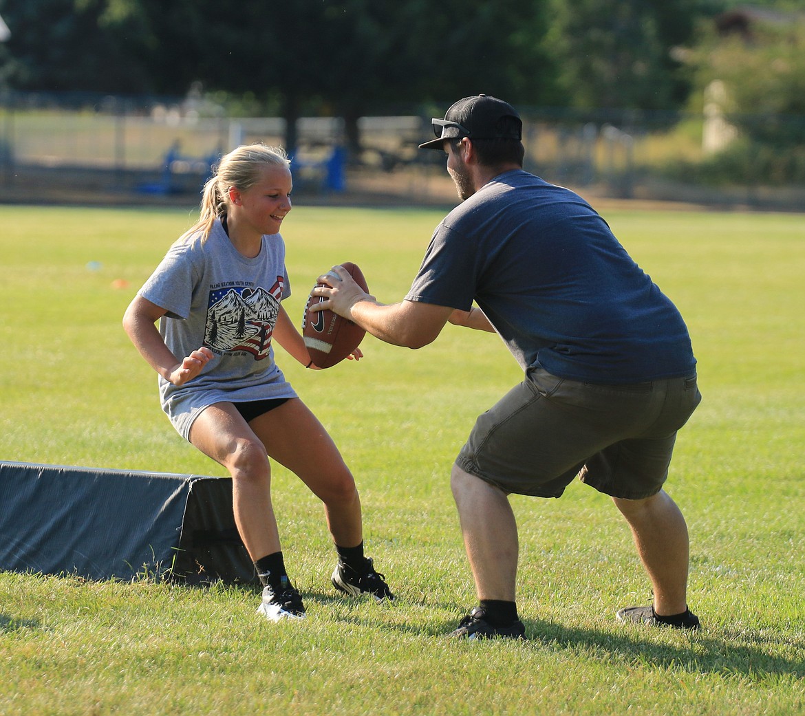 Clark Fork rising seventh grader Hannah Raynor participates in a blocking drill with Clark Fork High head football coach Patrick Young.