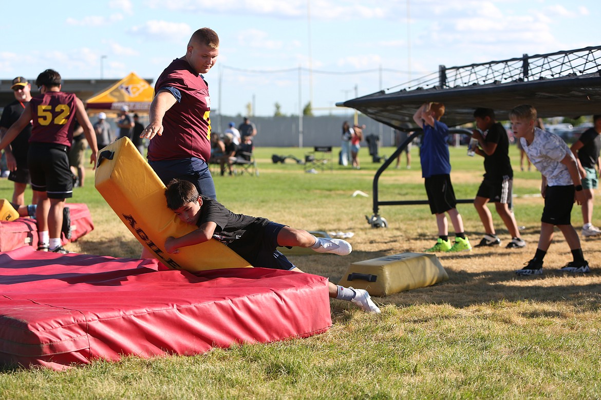 With a current Moses Lake High School football player holding the tackling bag, a youth player dives in for a tackle on Tuesday at the Mav Youth Football Camp.