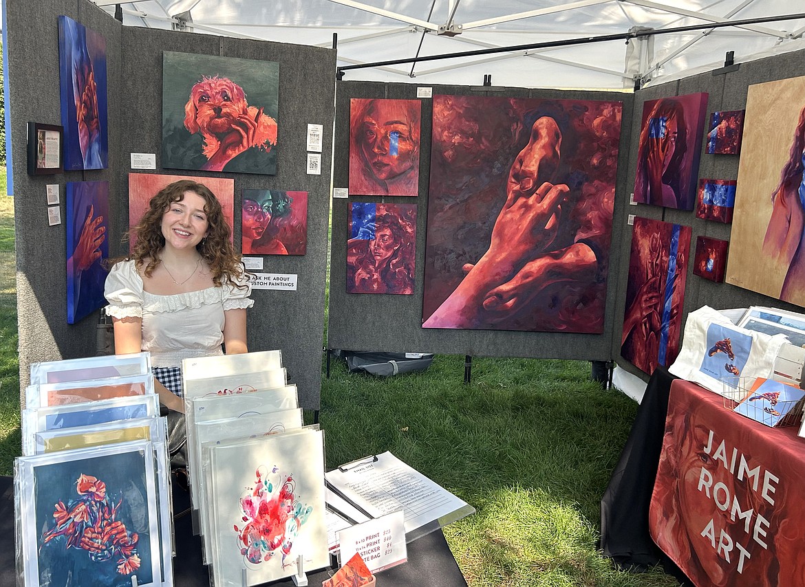 Jaime Rome sits with her art at the Taste of Coeur d'Alene in City Park on Friday.