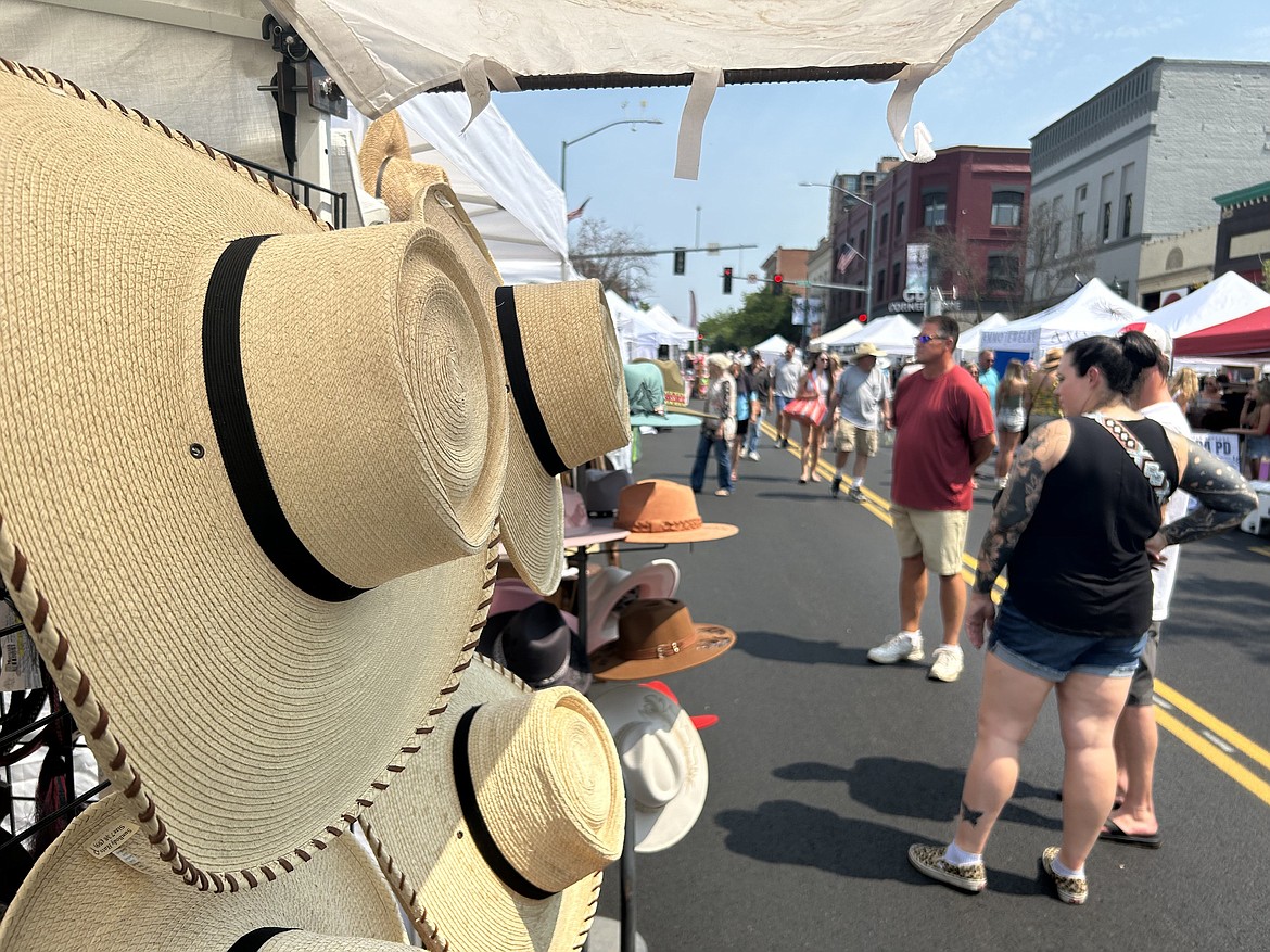 Hats offered by Leia Fox, owner of Leia Fox Designs, are displayed at the Street Fair in Coeur d'Alene as crowds wander nearby on Friday.