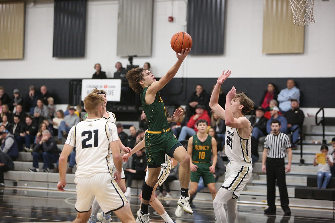 Quincy point guard Pierce Bierlink, in green, rises toward the rim for a layup during a game against Royal in the 2023-24 season.