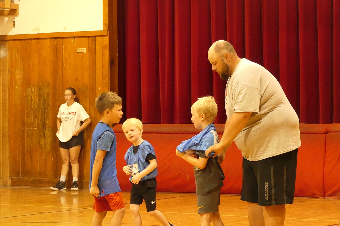 Camp instructor and Hot Springs AD Brady Ovitt helps a K-2 player get his scrimmage jersey on during last week's Hot Springs Basketball Camp. (Chuck Bandel/VP-MI)