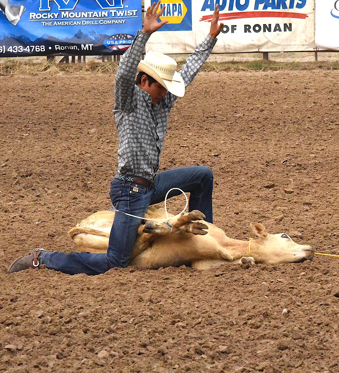 Joshua Skunkcap throws up his hands to signal time as he finishes tying his calf. (Berl Tiskus/Leader)