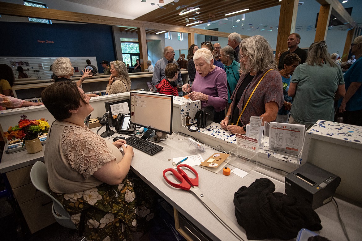 Mari Schowachert (center) is the first person to get their library card at the new Bigfork library during its opening Tuesday, August 6. (Avery Howe/Bigfork Eagle)