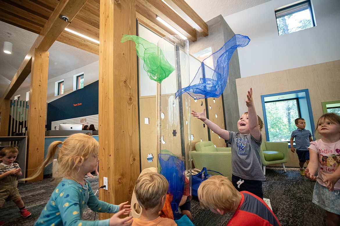 Kids play with a scarf-launching tube in the children's area of the new Bigfork library, a fan favorite, during its grand opening Tuesday, August 6. (Avery Howe/Bigfork Eagle)