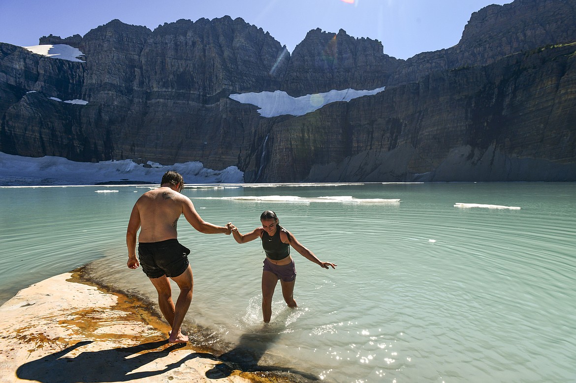 Braxton Smith gives a hand to Suzanne Buttenob after going for a brief swim in Upper Grinnell Lake in Glacier National Park on Thursday, Aug. 1. Smith and Buttenob drove through the night from Salt Lake City to hike the Grinnell Glacier trail. (Casey Kreider/Daily Inter Lake)