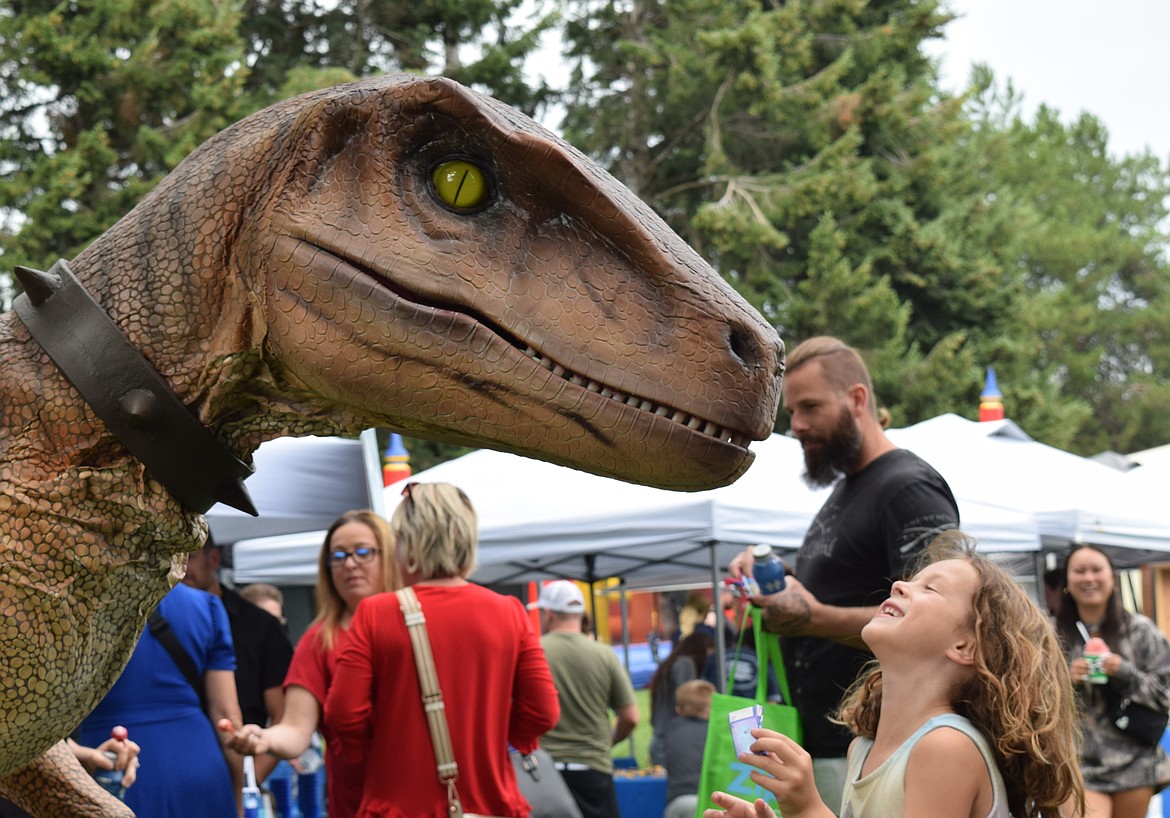 Ruth Beremore laughs as she feeds candy to Stanley the Velociraptor, who made an appearance during National Night Out at McIntire Family Park Tuesday. Stanley is a popular mascot at Hayden's Triple Play Family Fun Park. Photos by Hailey Hill