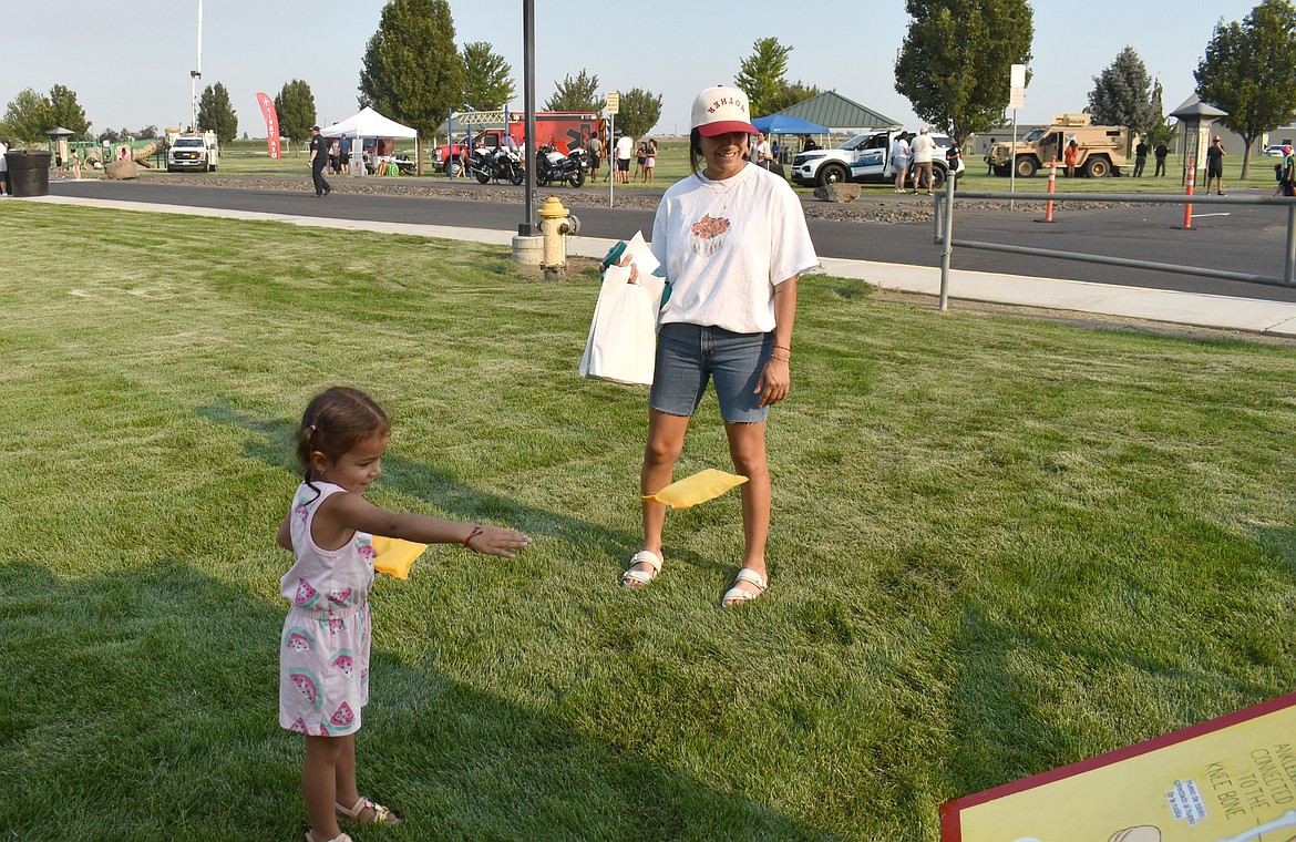 Three-year-old Haisley Villalpando lets fly a bean bag at National Night Out in Quincy Monday.