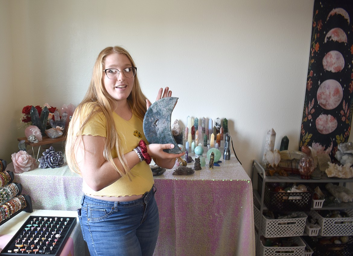 Tia Seibel, owner of Fairygenix Crystals, shows a crescent moon made of moss agate.  Seibel offers a variety of crystal home decorations.