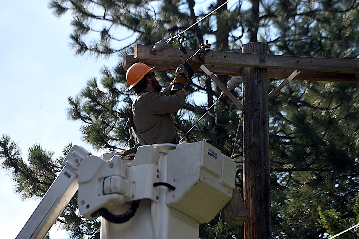 A Flathead Electric worker checks a line on a pole above a small fire early Wednesday evening on Rawlings Road just outside Libby. (Scott Shindledecker/The Western News)