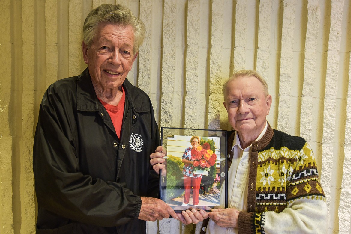 Martin Rippens, left, and Jesse Malone, right, hold a photo of longtime Montana Dahlia Society member Sharon Askelson. (Kate Heston/Daily Inter Lake)