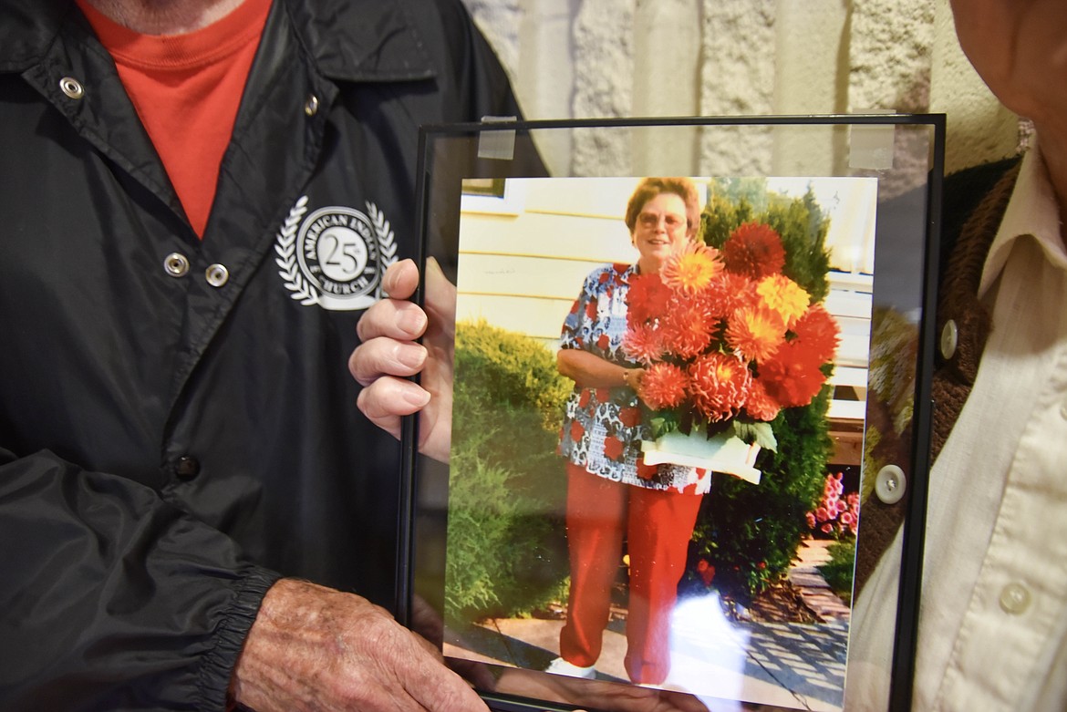 Martin Rippens, left, and Jesse Malone, right, hold a photo of longtime Montana Dahlia Society member Sharon Askelson. (Kate Heston/Daily Inter Lake)