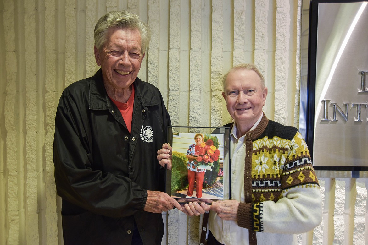 Martin Rippens, left, and Jesse Malone, right, hold a photo of longtime Montana Dahlia Society member Sharon Askelson. (Kate Heston/Daily Inter Lake)