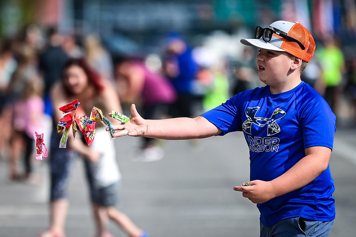 A child tosses a handful of candy to specators during the Northwest Montana Fair Parade in Kalispell on Friday, Aug. 9. (Casey Kreider/Daily Inter Lake)