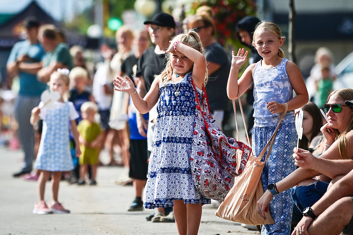 Children wave and watch the Northwest Montana Fair Parade in Kalispell on Friday, Aug. 9. (Casey Kreider/Daily Inter Lake)