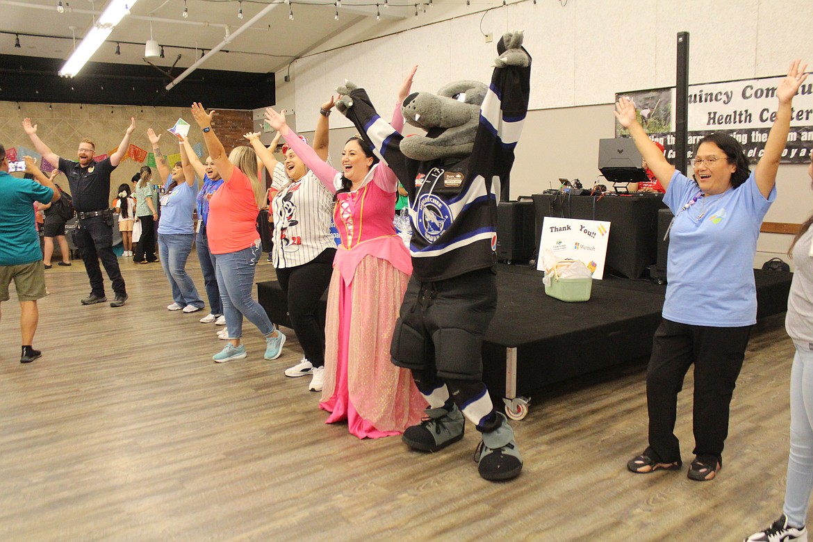 Volunteers, including Walt from the Wenatchee Wild, center, rock the YMCA dance during the Quincy Community Health back-to-school event.