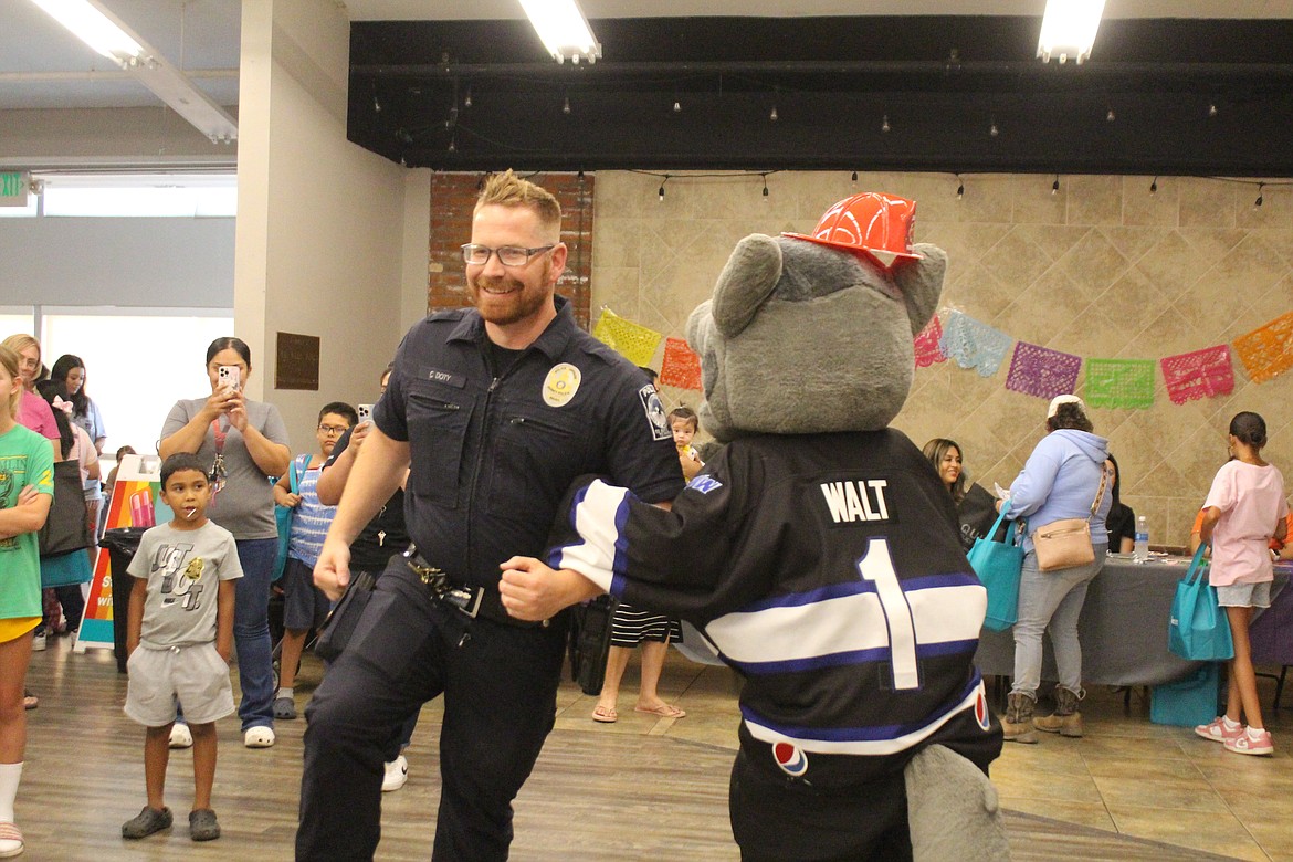 Quincy Police Officer Chris Doty, left, and Walt from the Wenatchee Wild go round and round in the chicken dance at the Back to School health fair.