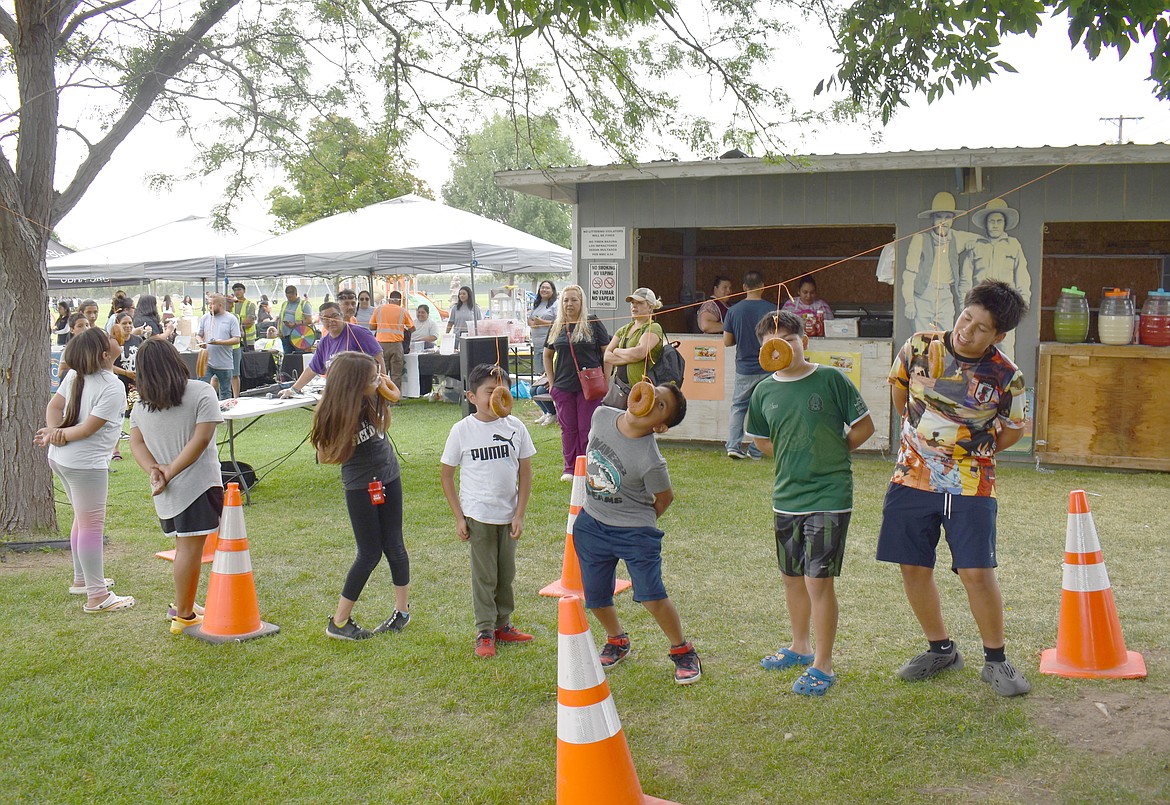 Contestants vie to consume dangling donuts at National Night Out in Mattawa Friday. Mattawa combines the event, which brings out police and firefighters to mingle with the public, with a community festival that includes contests, music and a back-to-school raffle.