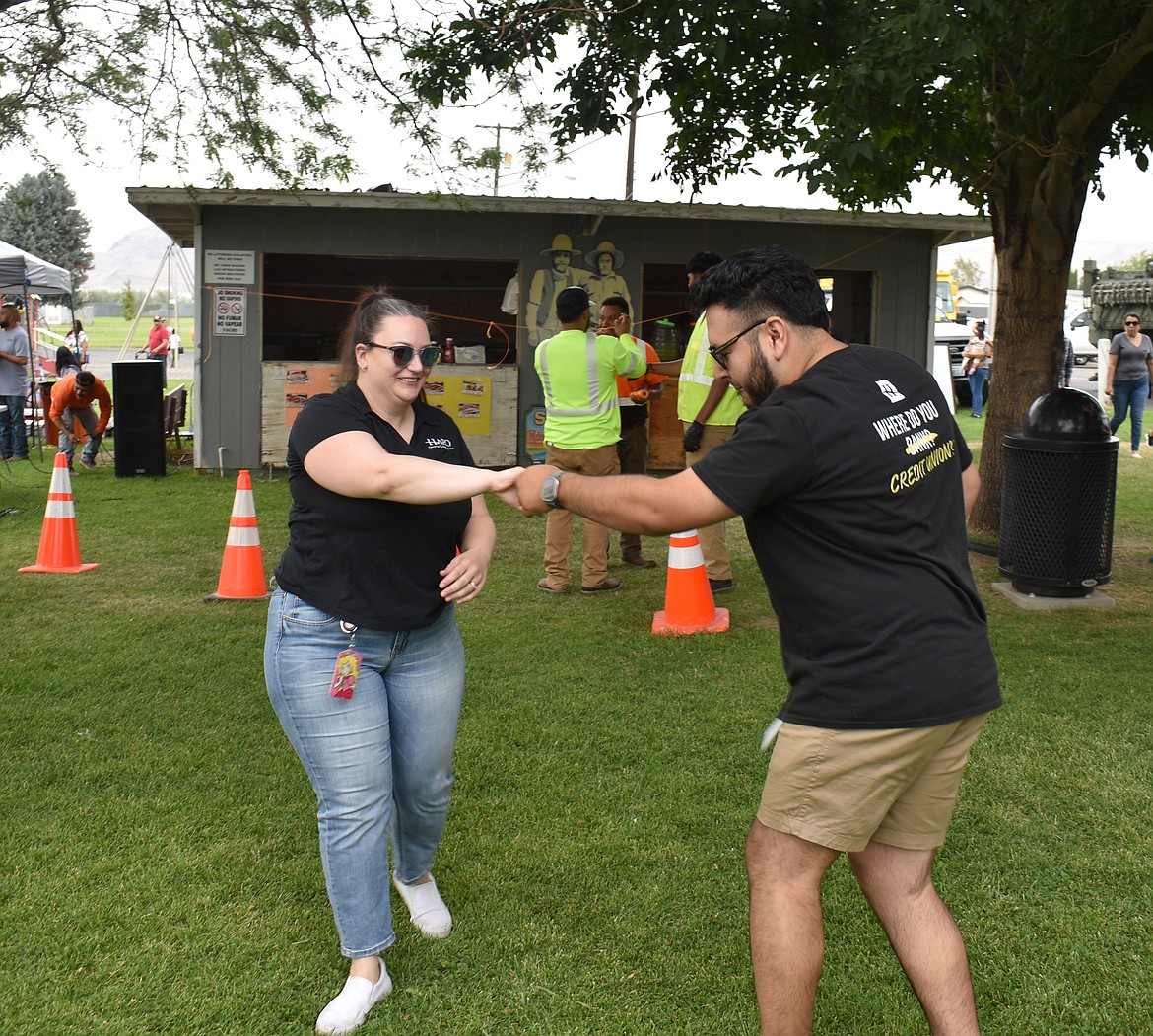 Michelle Hill, left, and Alejandro Fernandez show a little fancy footwork at National Night Out at Hund Park in Mattawa Friday. The pair were representing HAPO Credit Union at a vendor booth.