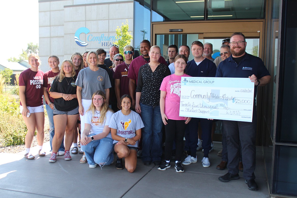 With students there to accept it, Dr. Luther Thompson, far right, presents a $25,000 check to the Community Athletics and Activities Association on behalf of the Wenatchee Valley Medical Group Monday.