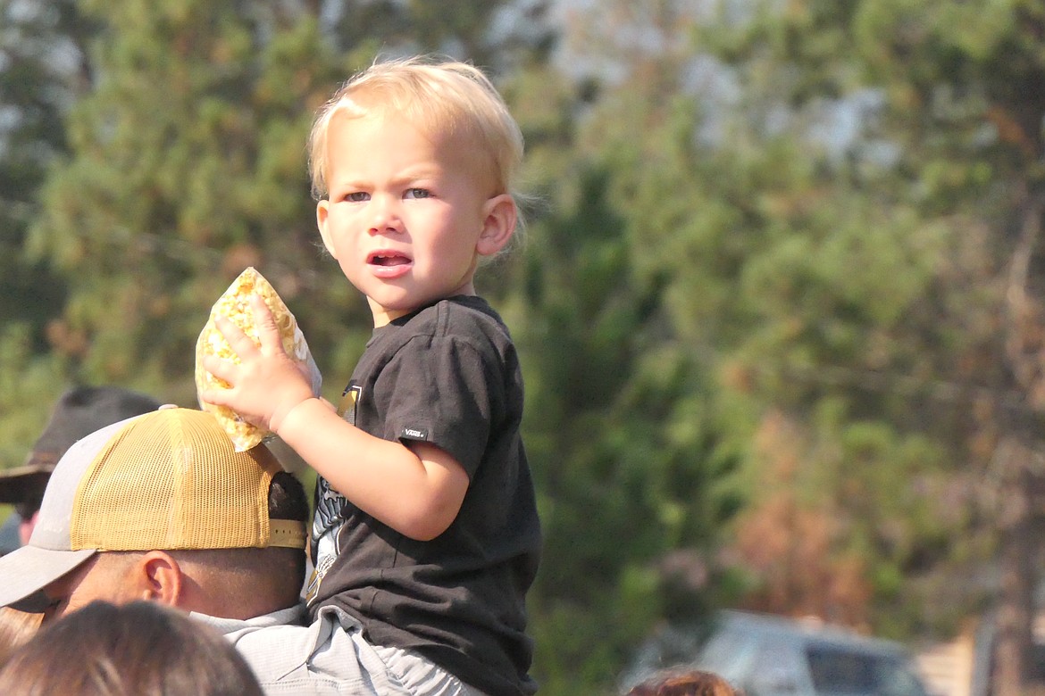 A young festival goer hangs onto a bag of popcorn while waiting for the Huckleberry Festival parade to begin.  (Chuck Bandel/VP-MI)