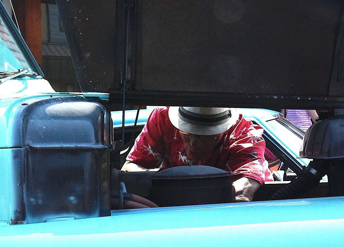 Michael Matt takes a look under the hood of his friend Mike Keeley's 1951 turquoise Dodge pickup.  (Berl Tiskus/Leader)