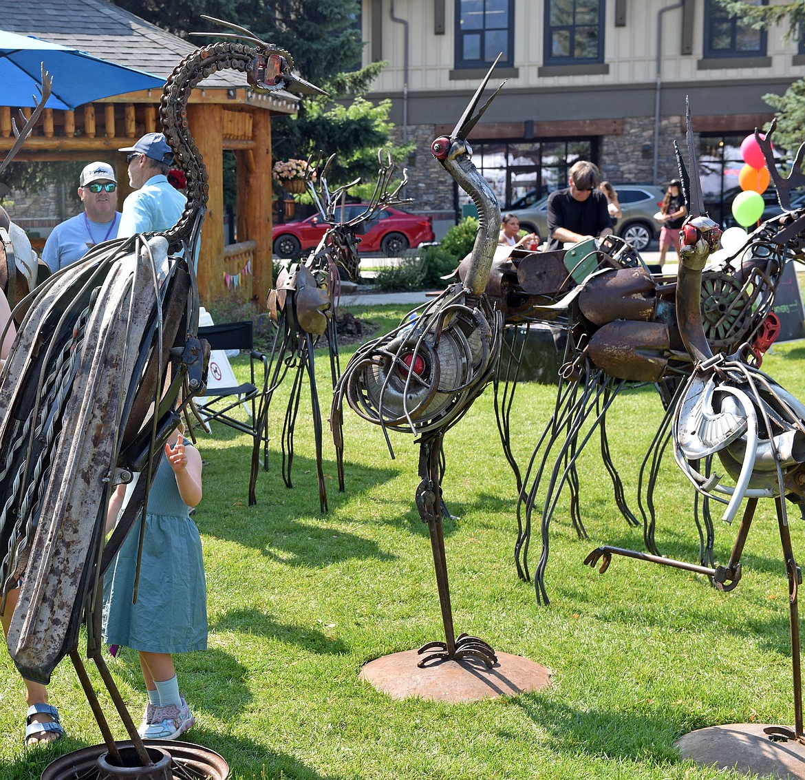 Visitors admire sculptures by Malen Pierson from Utah. While Pierson is new to the festival, his sculpture of a metal horse can be seen on Baker Avenue in front of Five Star Rentals. (Kelsey Evans/Whitefish Pilot)