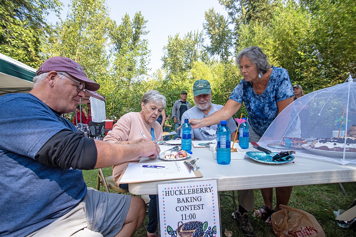 Judges Bob Martin, Janica Williamson and Garth Gallagher work with coordinator Cindy Love to decide the winner of the Swan Lake Huckleberry Festival baking contest Saturday, Aug. 10. (Avery Howe/Bigfork Eagle)