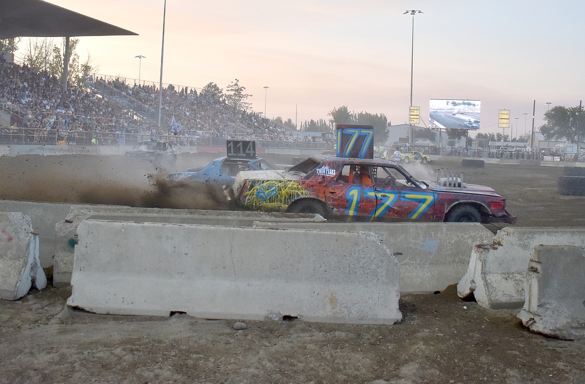 Demo cars driven by Edgar Martinez, left, and Lyle Wayne Jr. kick up a spray of dirt at the Agri-Service Demo Derby Tuesday.