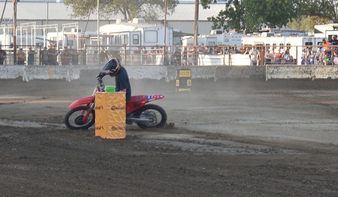 A dirt bike barrel racer rounds a barrel at the Agri-Service Demo Derby Tuesday, just a split second before laying his steel steed down in the dirt.