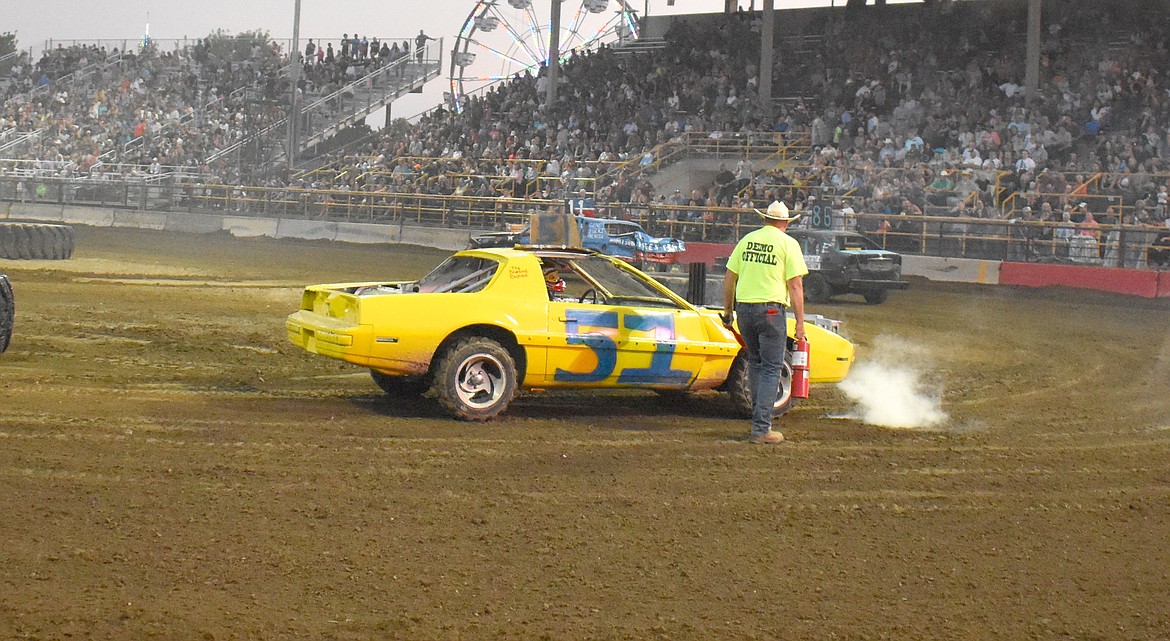 An Agri-Service Demo Derby official extinguishes a small fire that ignited in Andrew Gonzalez’s engine compartment Tuesday.