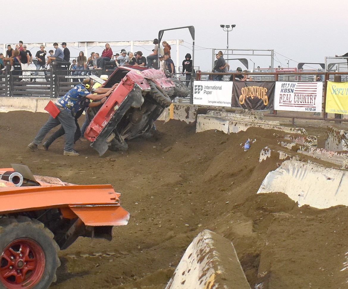 Agri-Service Demo Derby personnel tip Zack Moore’s car back onto its wheels after Moore rode up the concrete barrier and his car landed on its driver’s side.