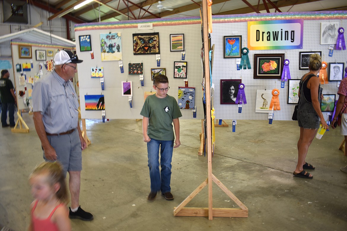 Attendees at the Grant County Fair Wednesday look over paintings and drawings in the Arts & Crafts Building. There were categories for all ages and media.