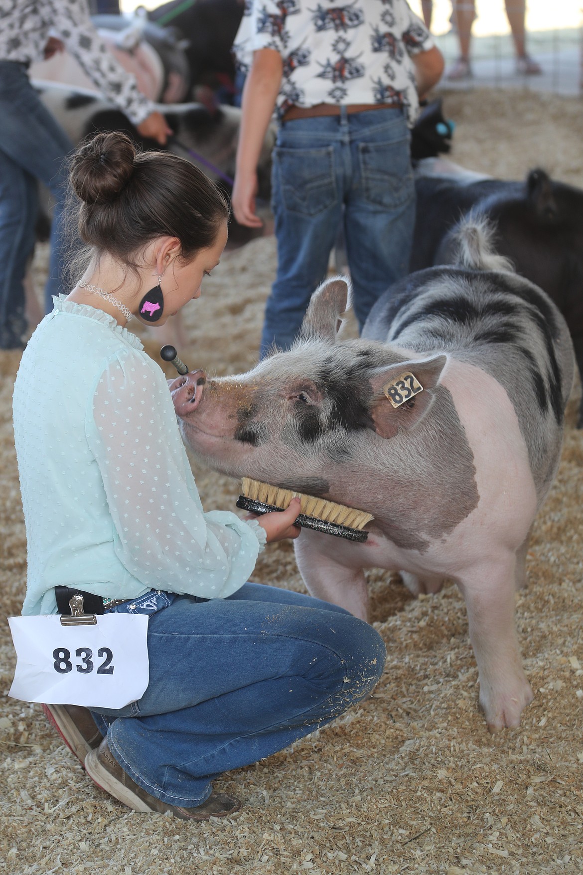 Hailey Van Pelt, a member of the Gold 'n' Grouse 4-H Club bends down to pet her pig during a competition at the Bonner County Fair on Wednesday.