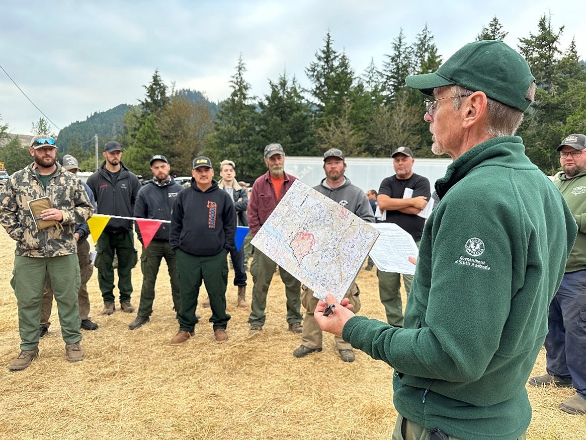 Safety Officer Cameron Ward from Australia gives a morning safety message to crews before they head to the fireline. 65 firefighters from Australia and New Zealand are in the Pacific Northwest helping with blazes.