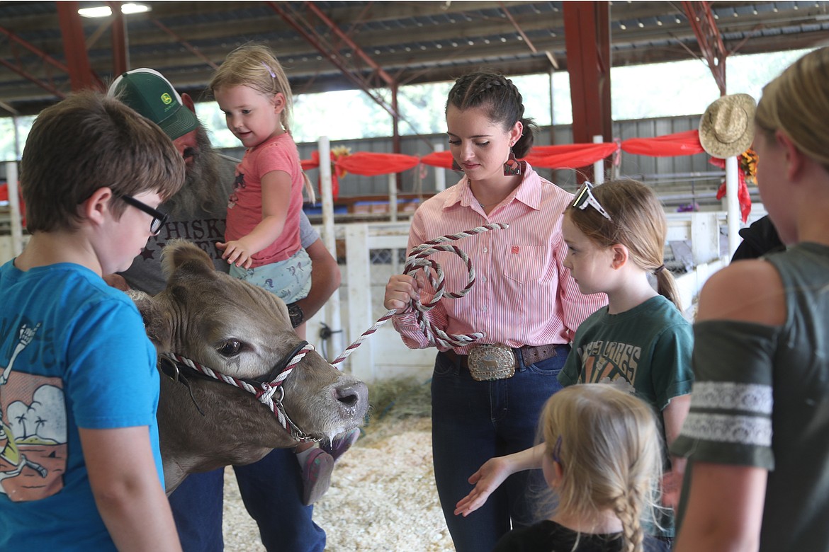 Kaylee McCown and her steer, Trump are surrounded by youngsters curious about the steer and wanting to know it they can pet it.