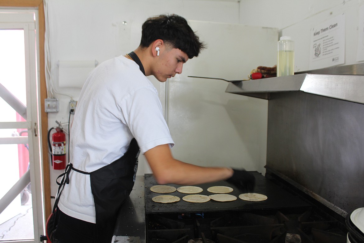 Julian Campos heats up tortillas in the booth operated by Our Lady of Fatima Catholic Church as a fundraising project.